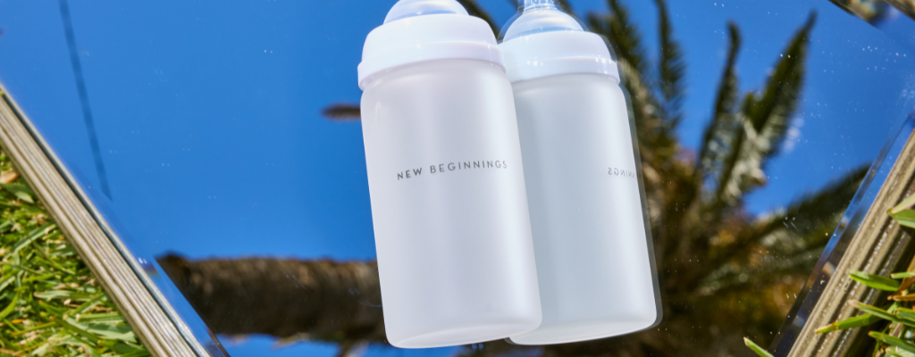 new beginnings glass baby bottle flat lay on mirror